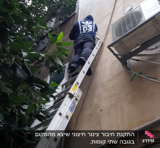אדם על סולם ליד צינור חיצוני על קיר